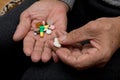 An elderly man holds a lot of colored pills in old hands. Painful old age. Health care of older people.