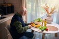 Elderly man at the kitchen table cuts vegetables for salad Royalty Free Stock Photo