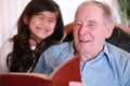 Elderly man and little girl reading Bible together Royalty Free Stock Photo