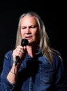 elderly man with long gray hair sings into a microphone Royalty Free Stock Photo