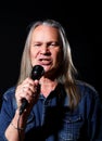 Elderly man with long gray hair sings into a microphone Royalty Free Stock Photo