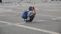 An elderly man with long gray hair is squatting on a smartphone taking pictures of the sights of the big city.