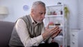 Elderly man looking at palms, thinking about life, aging process, retirement