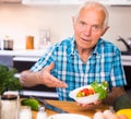 Elderly man made a fresh vegetable salad at home Royalty Free Stock Photo