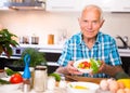 elderly man made a fresh vegetable salad at home Royalty Free Stock Photo