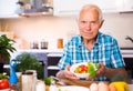 Elderly man made a fresh vegetable salad at home Royalty Free Stock Photo