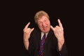 Elderly man making a horns gesture depicting heavy metal rock music Royalty Free Stock Photo