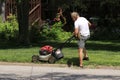 An Elderly Man Mowing his grass in his yard with a lawn mower on a Summer Day Royalty Free Stock Photo