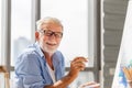 Elderly man painting on a canvas, Smiling mature man painting on canvas at home, Happy retirement concepts Royalty Free Stock Photo