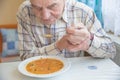 Elderly man with Parkinsons disease holds spoon in both hands Royalty Free Stock Photo