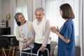 an elderly man patient being assist by home health nurse,using walker to walk at home Royalty Free Stock Photo