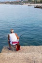 Elderly man is peacefully engaged in a fishing activity on a pier