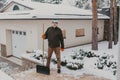 Elderly man with plastic shovel stands in snowy yard