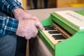 An elderly man plays a toy piano. Hands press the keys of an old children`s instrument Royalty Free Stock Photo