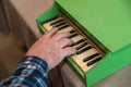 An elderly man plays a toy piano. His right hand is playing a jolly tune on an old children`s musical instrument Royalty Free Stock Photo