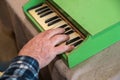 An elderly man plays a toy piano. His right hand presses the keys of an old children`s instrument. Royalty Free Stock Photo