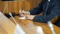 An elderly man - politician, lawyer or teacher writes on a piece of paper while sitting at a table in the boardroom. A court Royalty Free Stock Photo