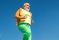 Elderly man practicing sports on blue sky background. Cheerful senior jogging in sportswear on sky background. Age is no Royalty Free Stock Photo