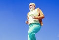 Elderly man practicing sports on blue sky background. Cheerful senior jogging in sportswear on sky background. Age is no Royalty Free Stock Photo