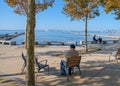 An elderly man on the promenade sits and looks at the Sea