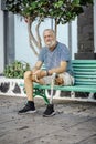 Elderly man with prosthetic leg. left rests sitting on a park bench. Spending a relaxing afternoon. People concept Royalty Free Stock Photo