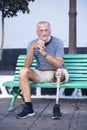Elderly man with prosthetic leg. left rests sitting on a park bench. Spending a relaxing afternoon. People concept Royalty Free Stock Photo
