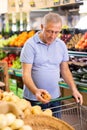Elderly man purchaser buying onions in grocery store