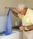 Elderly Man Putting Shirt in Washing Machine.