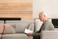 Elderly man reading book in living room Royalty Free Stock Photo