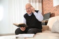 Elderly man reading book on sofa Royalty Free Stock Photo