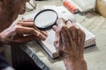 Elderly man reading writings in a notebook with magnifying glass near the window at home Royalty Free Stock Photo