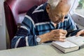 Elderly man reading writings in a notebook with magnifying glass near the window at home Royalty Free Stock Photo