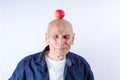 Elderly man with red apple on head with wrinkled face with fear grimace