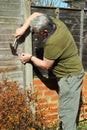 Elderly man repairing a fence. Royalty Free Stock Photo