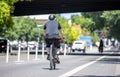 An elderly man rides a bicycle on a dedicated bike path along a city street