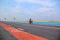 Elderly man riding motorcycle on Chaloem Phra Kiat 80 Phansa bridge, one of the most popular places in Thale noi, Phatthalung