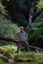 Elderly man after a rock climb watching and exploring waterfall in Wicklow Mountains in sunny day, Wicklow Mountains, Ireland