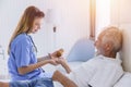Elderly man senior people lay on bed health care giving medicine pills from nurse at homecare