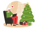 Elderly man sits in a armchair near Christmas tree and communicate with relatives on a laptop