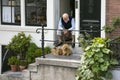 elderly man sits with two dogs in doorway of canal house in amsterdam