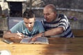 A elderly man sitting doing crosswords hobby with his grandson