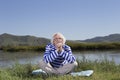 Elderly man sitting on a river bank Royalty Free Stock Photo