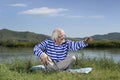 Elderly man sitting on a river bank Royalty Free Stock Photo