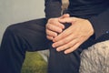 elderly man sitting on a sofa in the living room at home and touching his knee by the pain Royalty Free Stock Photo