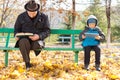 Elderly man and small boy sharing a park bench Royalty Free Stock Photo