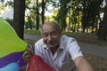 An elderly man with a smile on his face and bright balloons makes a selfie in the park Royalty Free Stock Photo