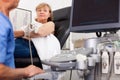 Elderly man sonographer using ultrasonography machine checking female patient in hospital diagnostic room