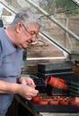 Elderly man sowing seeds in greenhouse.