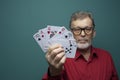 Elderly man showing a fan of poker cards.