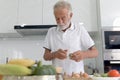 Elderly man standing at kitchen counter with colorful fresh vegetables, fruits and food ingredients, senior man preparing for Royalty Free Stock Photo